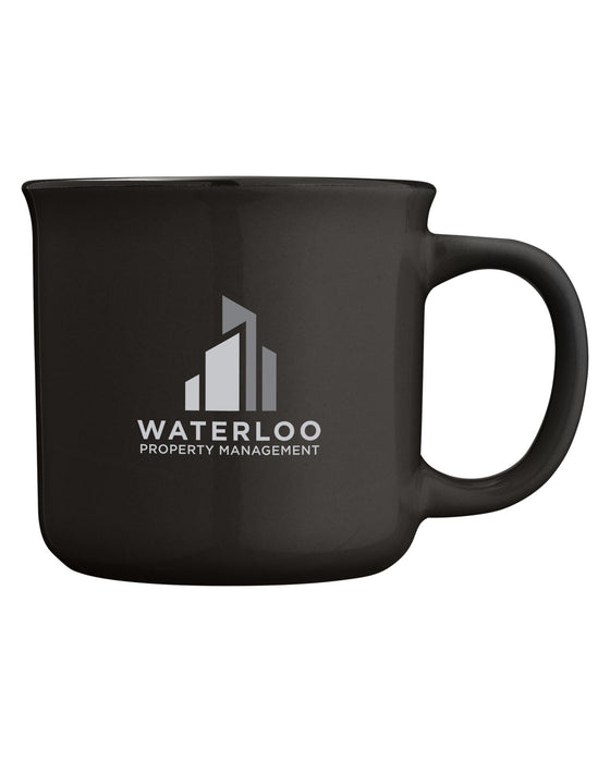 Closeup side view of a black ceramic mug with handle against a white background and a logo on the front with the words waterloo property management in white